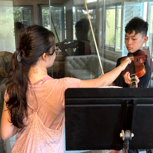 Erika Miller adjusts a violin student's posture